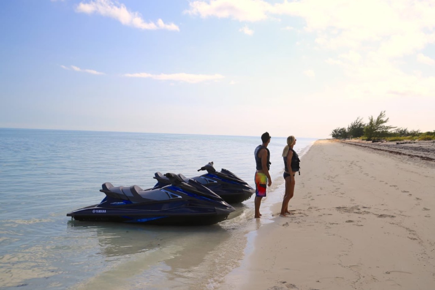 Jet skis pulled up on a sandy beach with the sea beyond